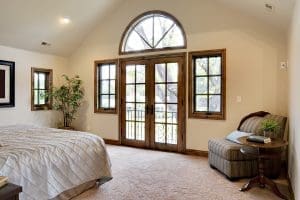 Custom Windows Appleton WI Interior of home with carpet flooring, queen size bed, and large wood frame custom windows.