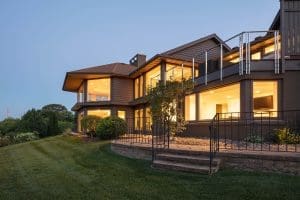 Exterior view of home during dusk. Home features large, modern windows that are illuminated by interior.