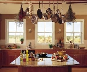 Replacement Windows Kaukauna WI Warm kitchen with wooden cabinetry, tan walls, and three windows with white frames