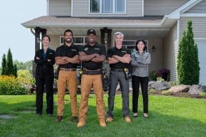 Best window replacement company. Team of Renewal by Andersen installers posing for photo in front of home.
